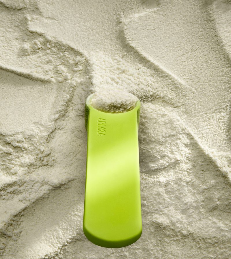 ARMRA Colostrum powder close-up with the brand’s neon measuring scoop